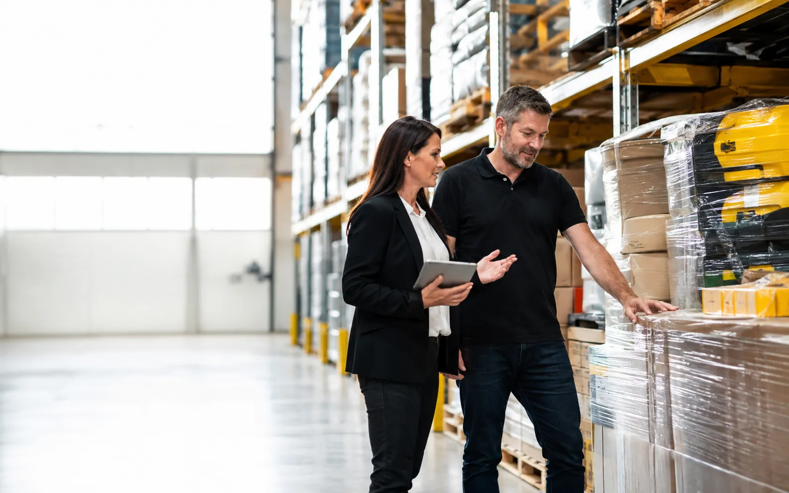 Wholesale buyer and supplier reviewing inventory in warehouse